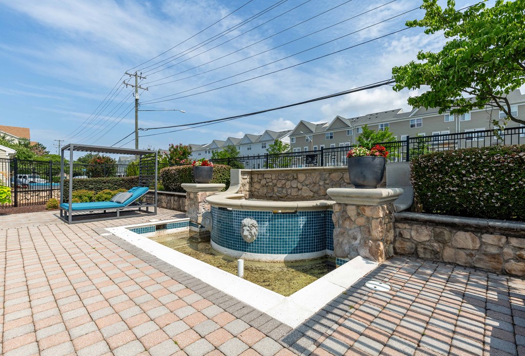 a backyard with a pool and a hot tub with a stone wall and a spa