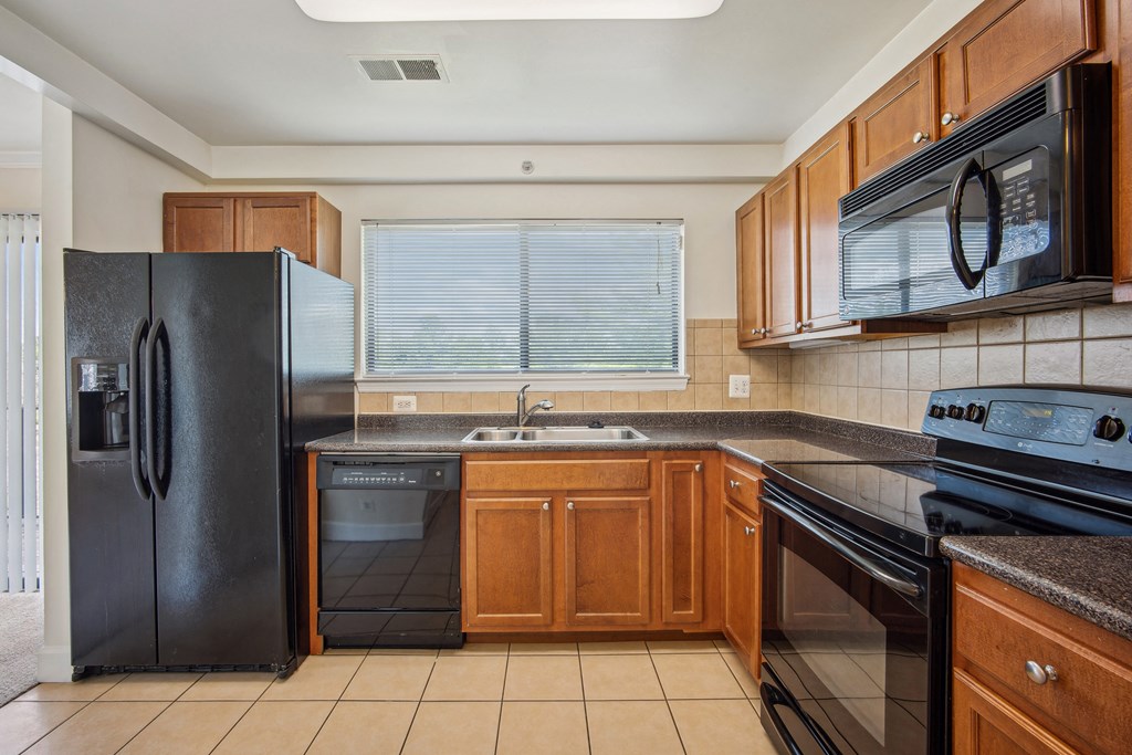A kitchen with black appliances and wooden cabinets at Elme Bethesda, Bethesda, 20814