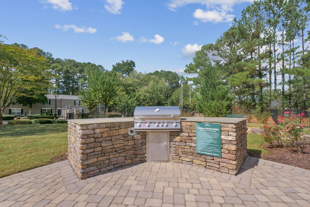 A stone grill area with a sign and a green board.
