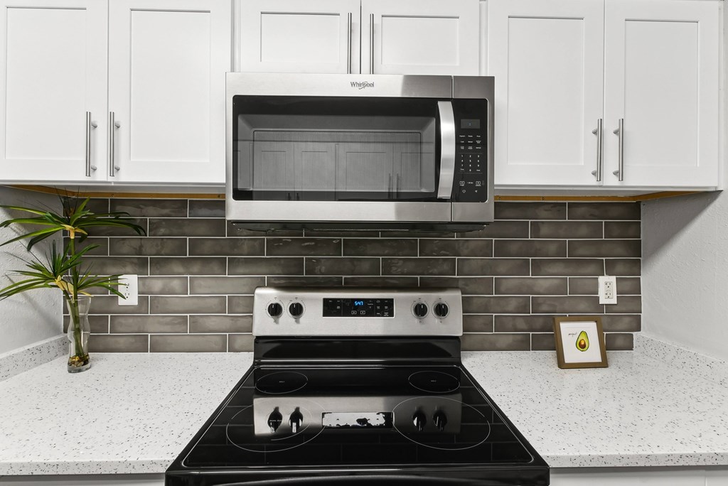 A modern kitchen with a black stove top and a white microwave above it.