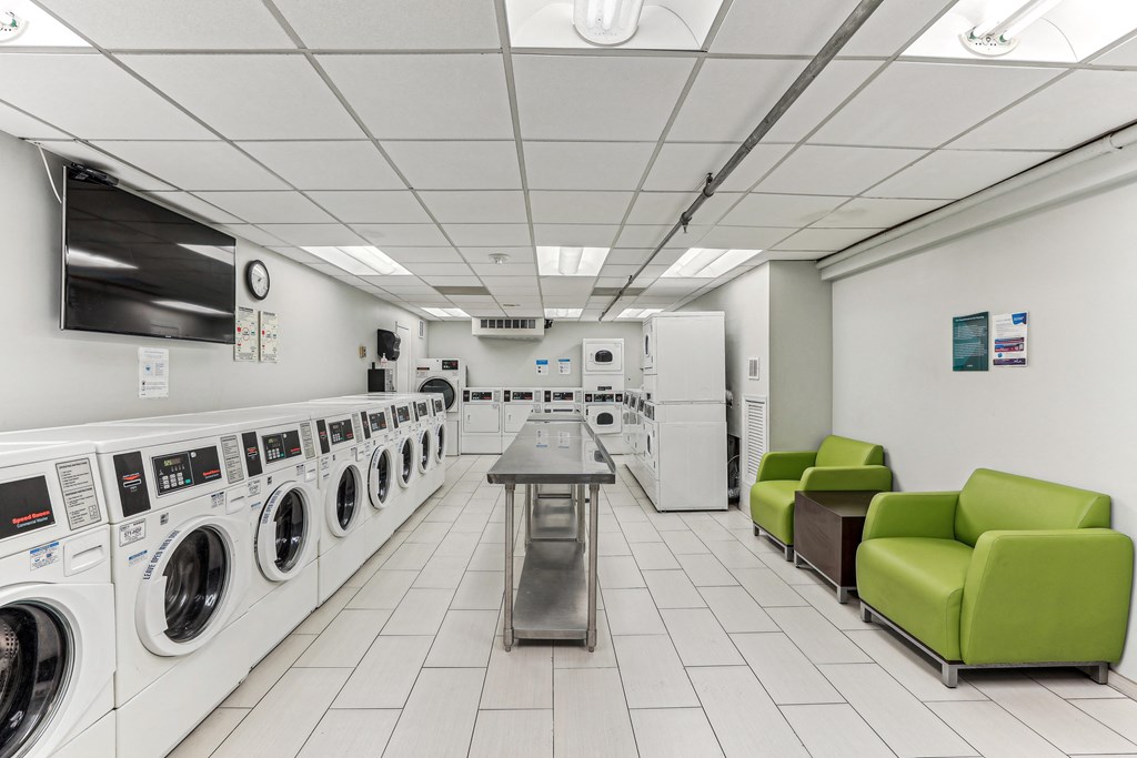 A laundromat with a row of washers and dryers on the left and a table and two chairs on the right at 3801 Connecticut Avenue, Washington, 20008