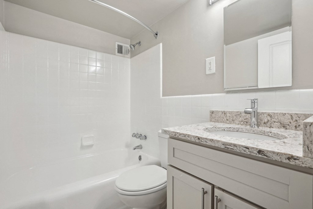 A white bathroom with a tub, toilet and sink at The Kenmore, Washington, 20015