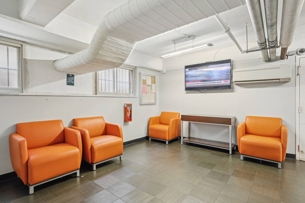 A room with orange chairs and a television mounted on the wall at The Kenmore, Washington, 20015