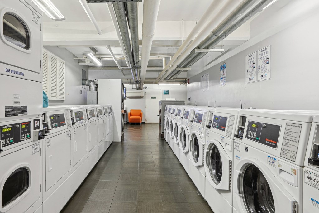 A row of industrial washing machines are lined up in a laundromat at The Kenmore, Washington, 20015