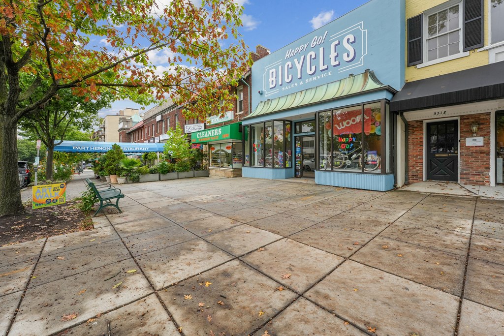 A bicycle shop is located in a plaza with a bench and trees near The Kenmore, Washington, 20015
