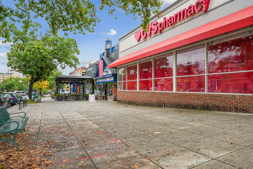 A red and white pharmacy with a green bench in front near The Kenmore, Washington, 20015