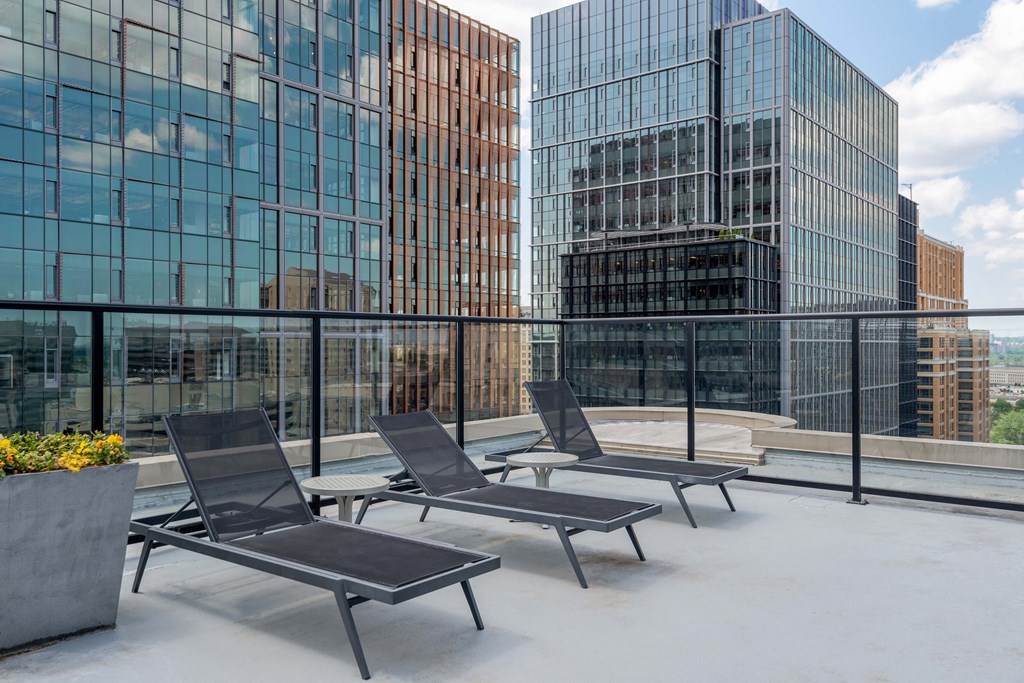 a group of lounge chairs on a rooftop terrace with tall buildings