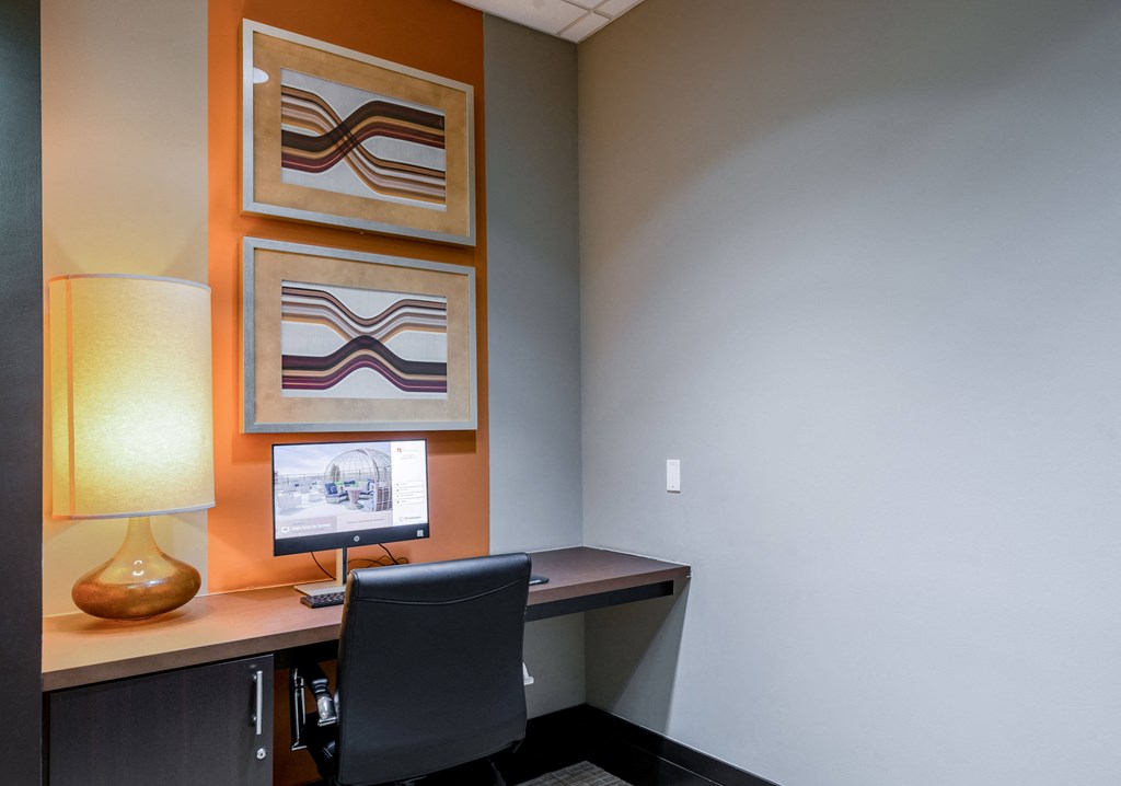 a desk with a computer and a lamp in a room