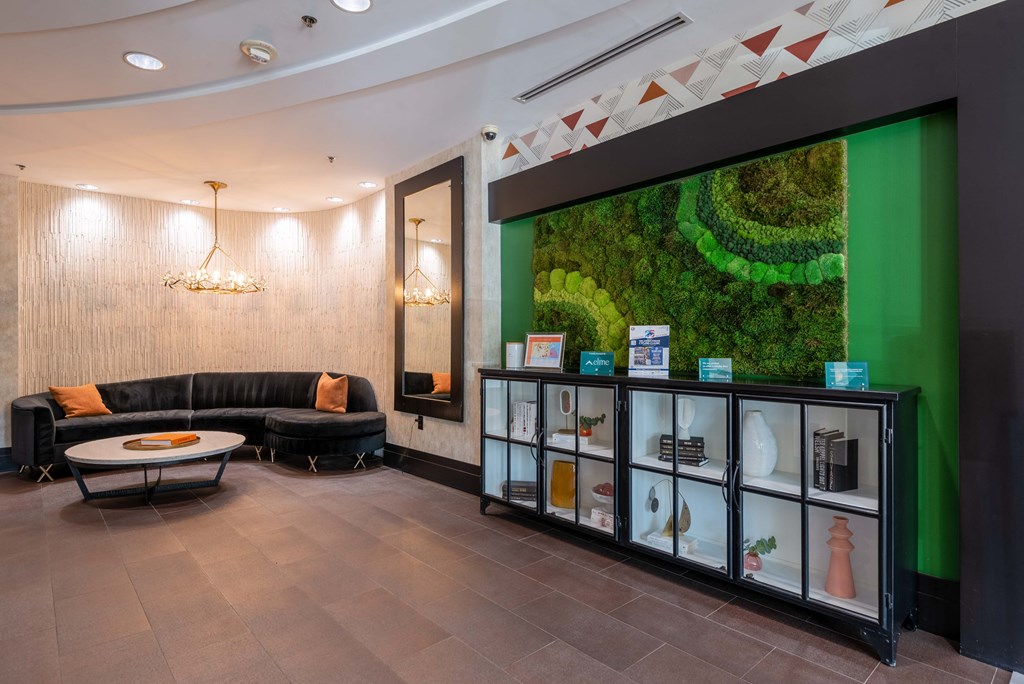 the lobby of a building with couches and a display case with a green wall