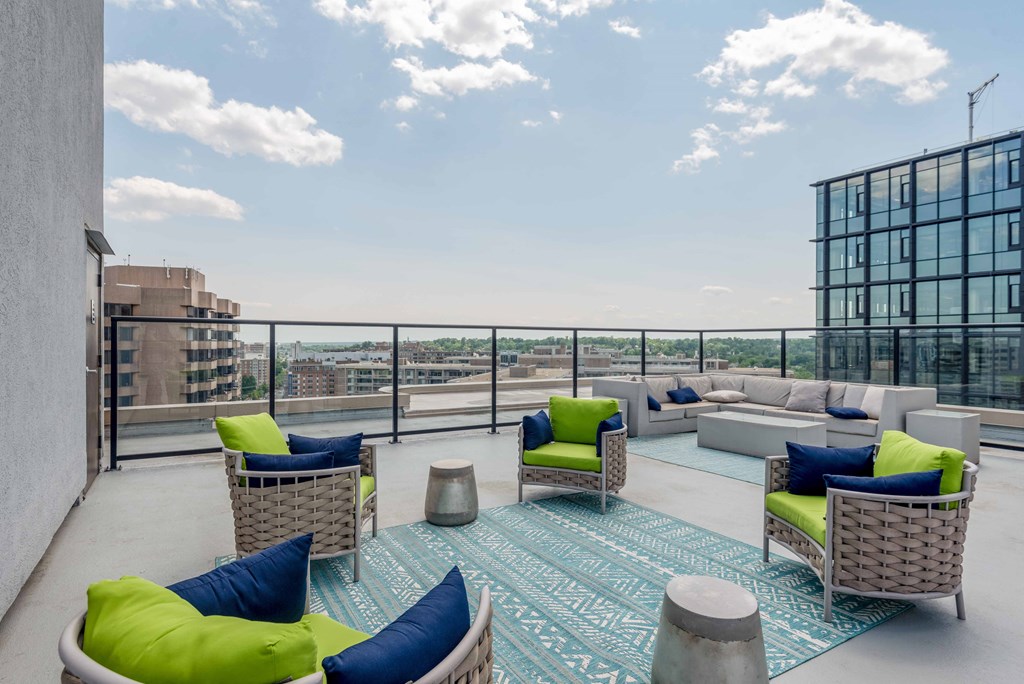 a communal area with couches and chairs and a rug on a balcony with a