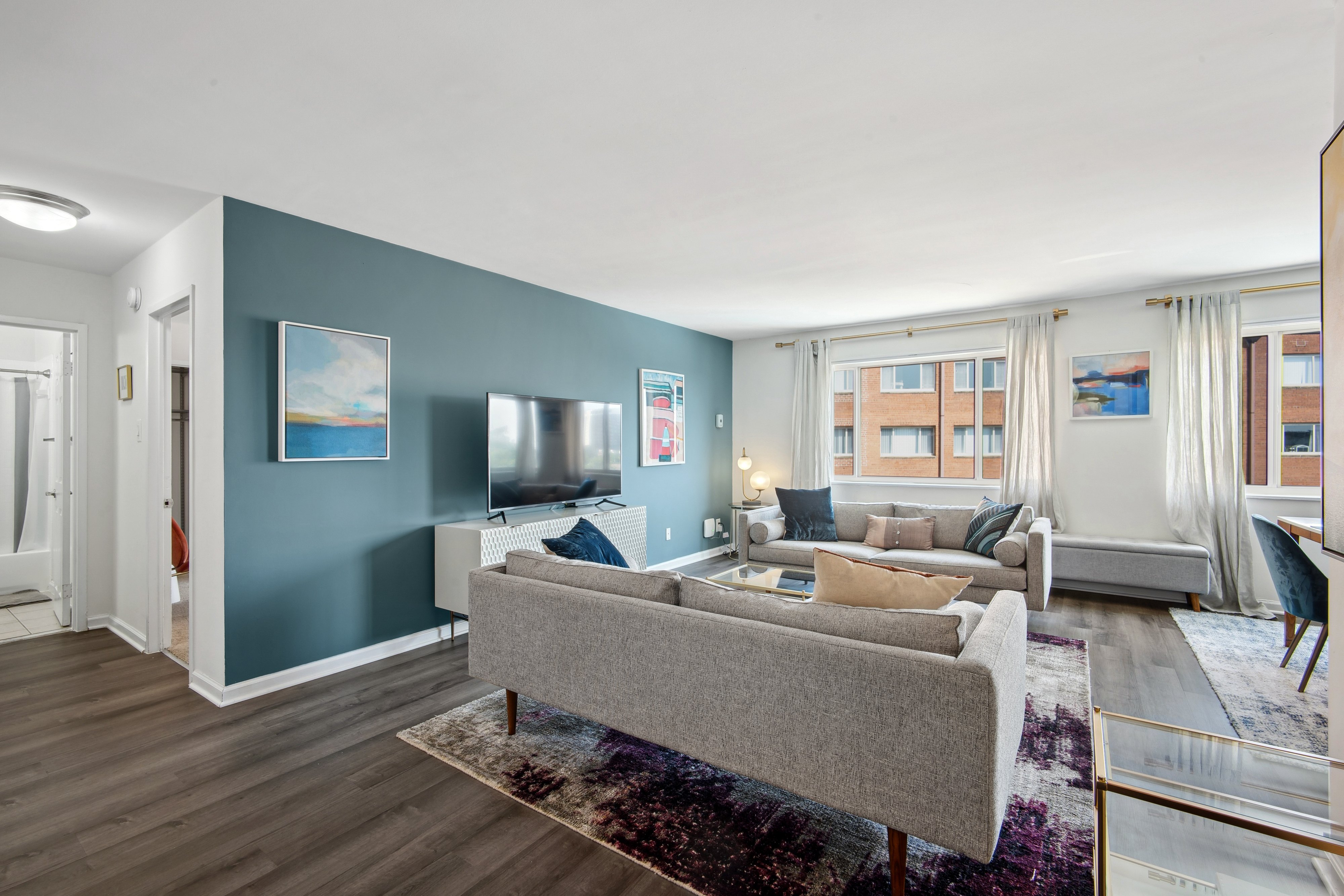 A living room with a grey couch and a rug.