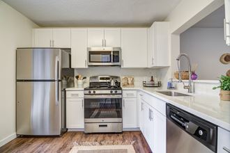 an open kitchen with stainless steel appliances and white cabinets