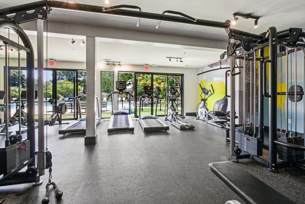A gym with a variety of equipment including treadmills, weights, and exercise machines.