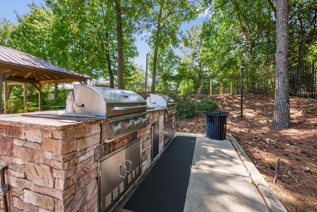 A BBQ grill is on a stone patio in a wooded areaat Elme Marietta Apartments, Marietta, GA