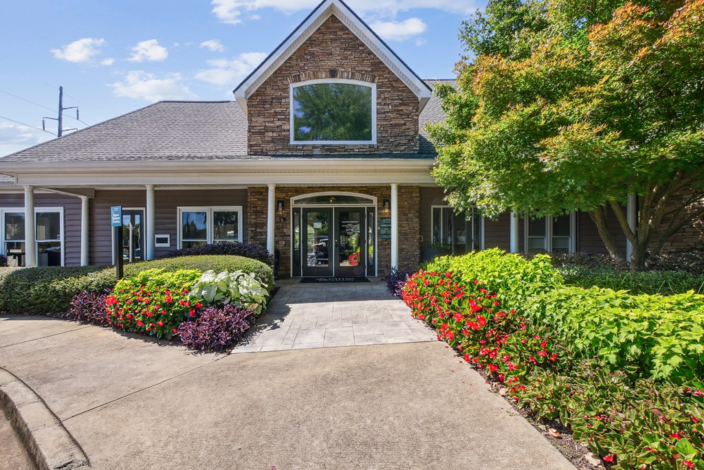A building with a grey roof and a glass window is surrounded by green bushes and trees at Elme Marietta Apartments, Marietta, GA