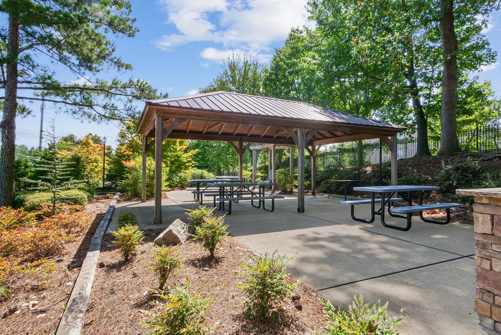 A pavilion with picnic tables is surrounded by trees and shrubs at Elme Marietta Apartments, Marietta, GA