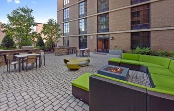 a patio with green couches and chairs and a fire pit in front of a brick building at Yale West, Washington, 20001