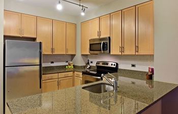 a kitchen with wooden cabinets and granite counter tops at Yale West, Washington, DC
