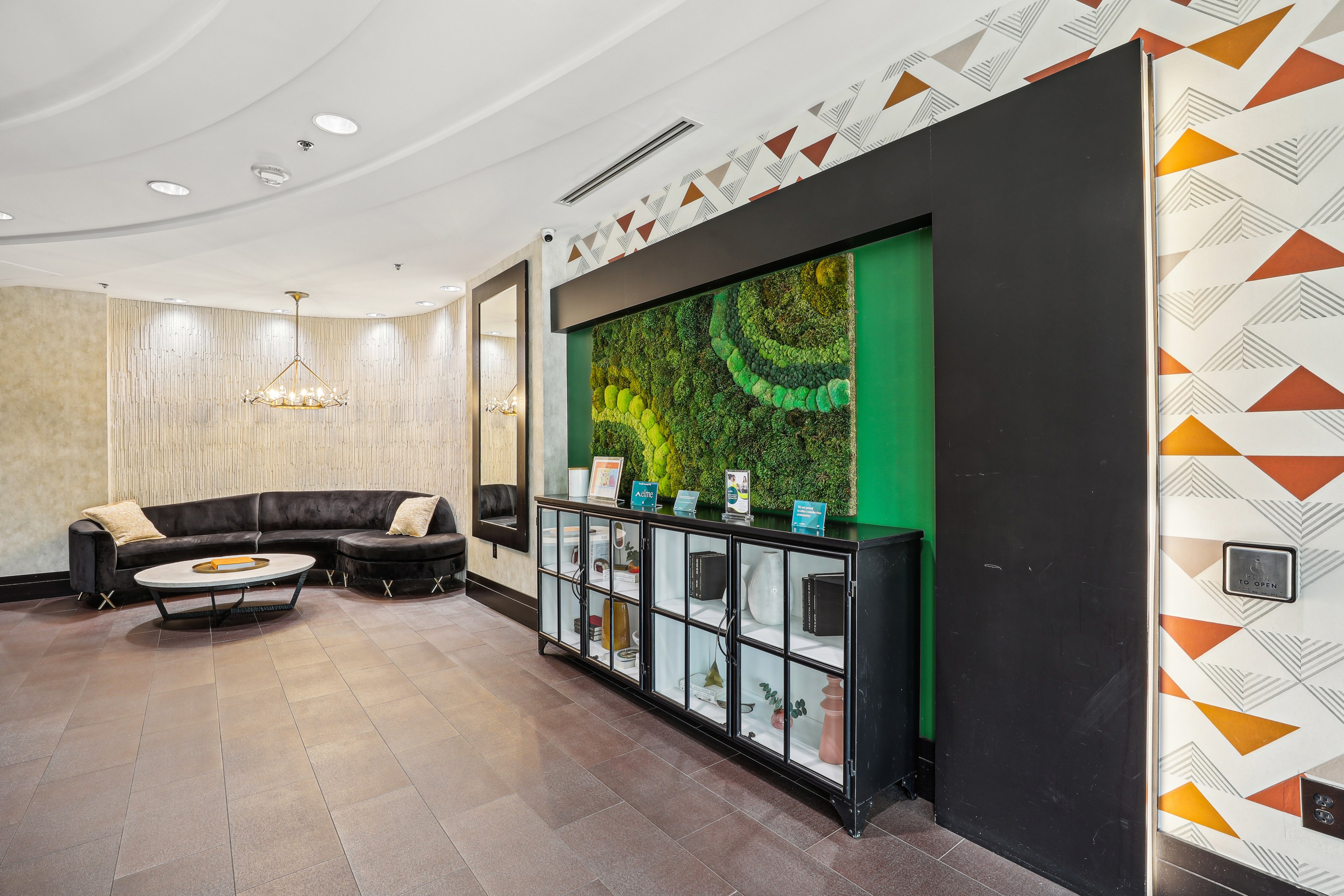 A modern living room with a black sofa and a glass cabinet.
