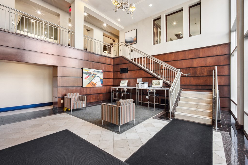 the lobby of a building with a staircase and chairs at Roosevelt Towers Apartments, Falls Church, Virginia