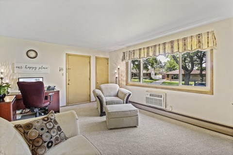 A living room with a couch, chair, and a window with a view of trees.