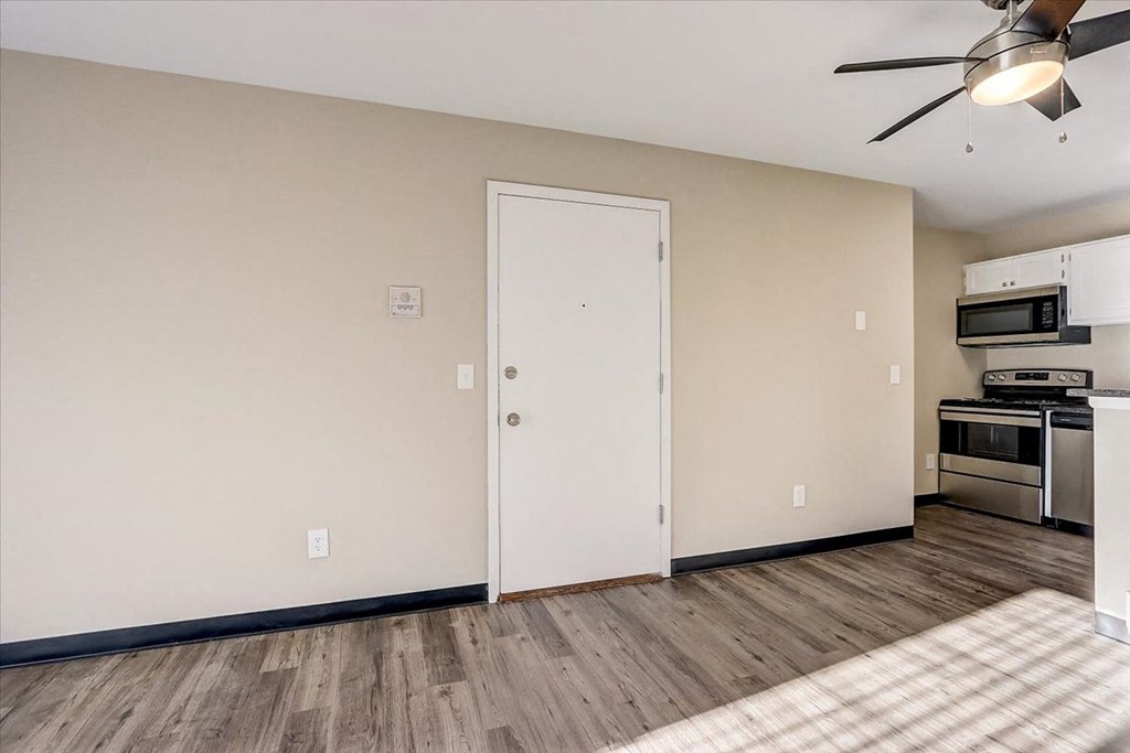 a living room with a kitchen and a ceiling fan