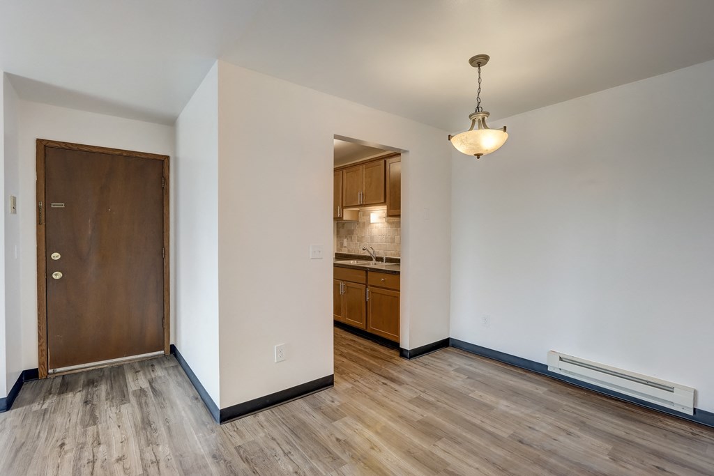 a bedroom with hardwood flooring and a door leading to a kitchen