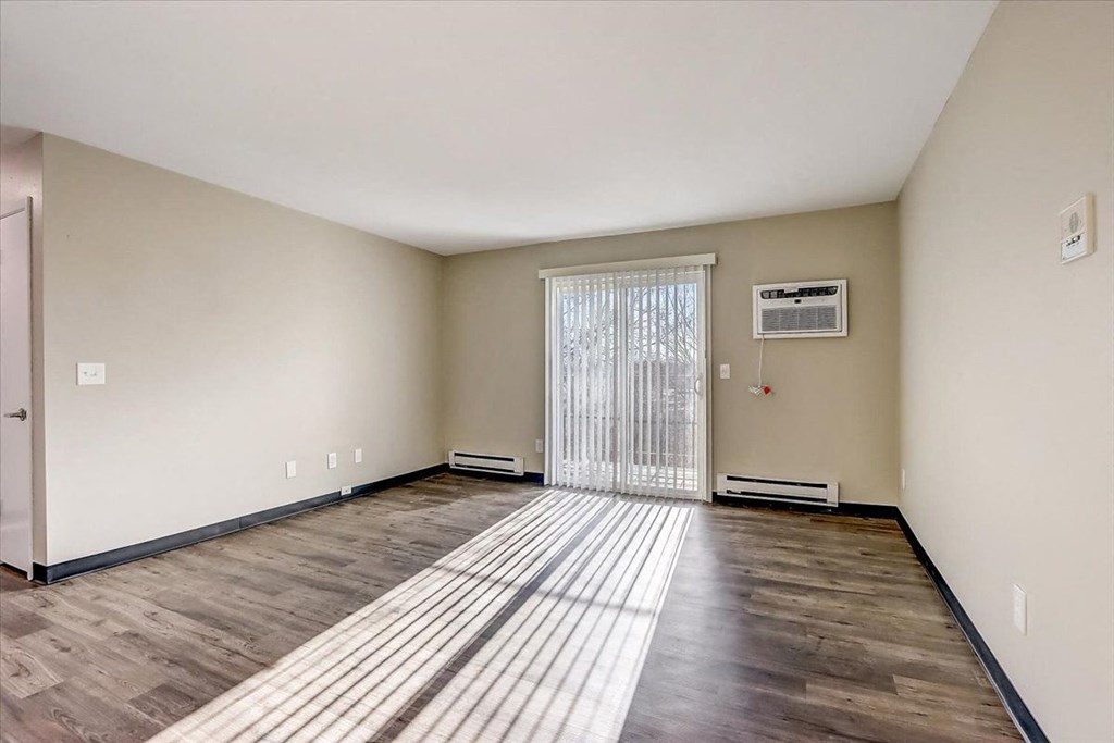 an empty living room with a sliding glass door and wood floors