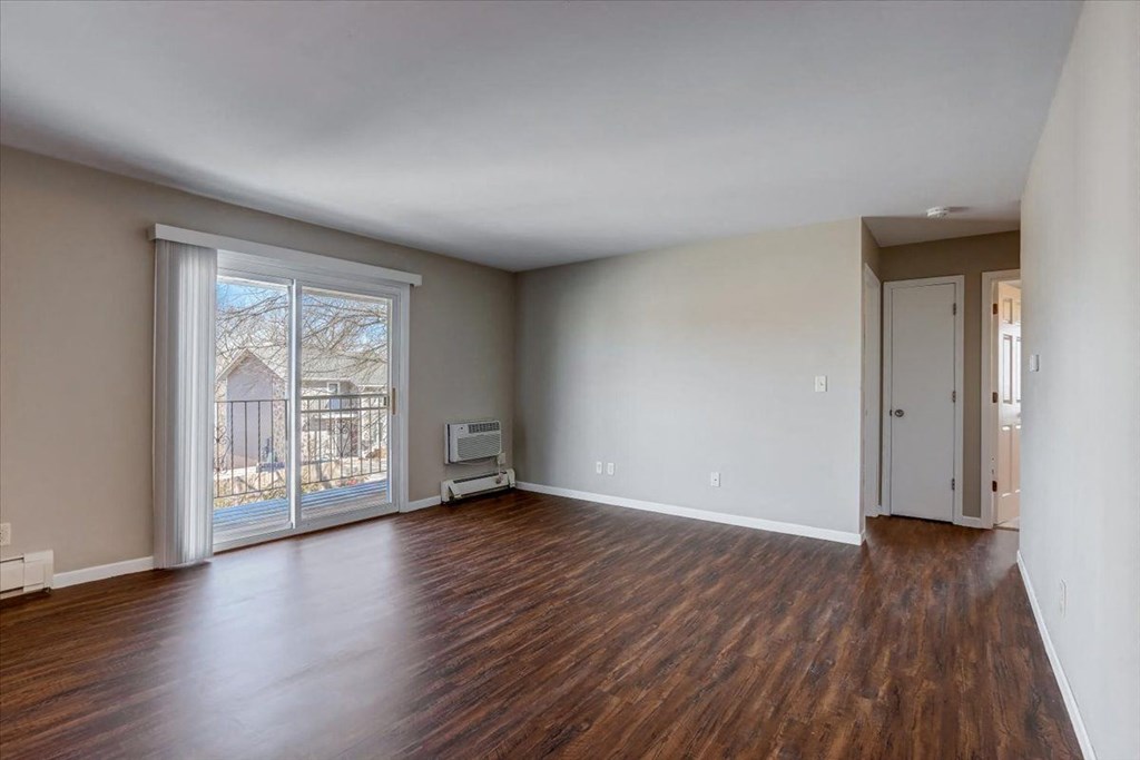 an empty living room with wood floors and a sliding glass door