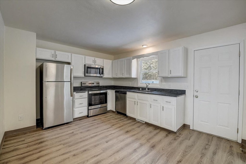 an empty kitchen with white cabinets and stainless steel appliances