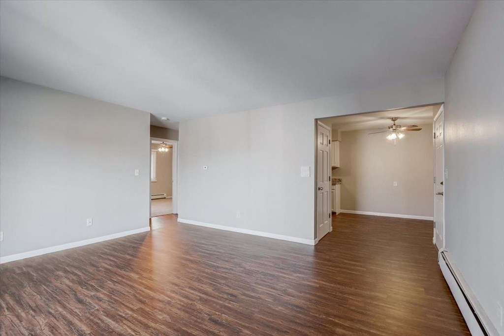 an empty living room with wood flooring and white walls