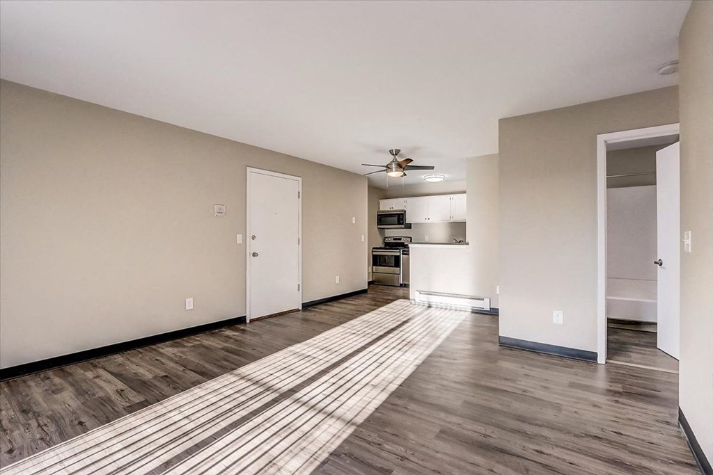 an empty living room and kitchen with a ceiling fan