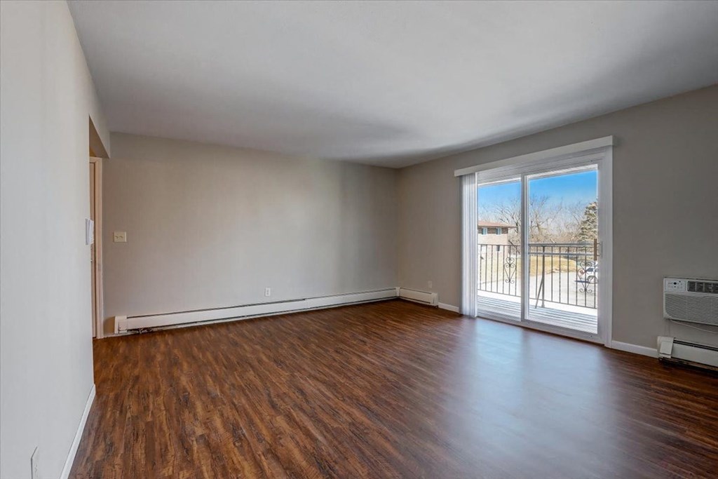 an empty living room with a sliding glass door to a balcony