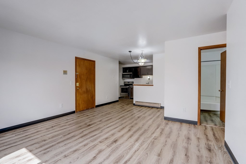 a living room with a hardwood floor and a kitchen in the background