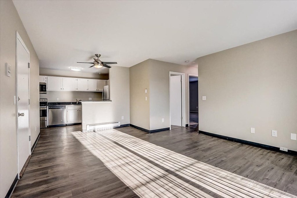 an empty living room and kitchen with a ceiling fan
