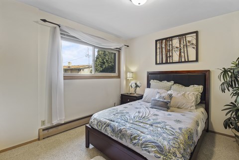 A bedroom with a bed, nightstand, and window.