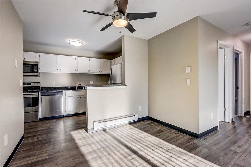 an empty living room and kitchen with a ceiling fan