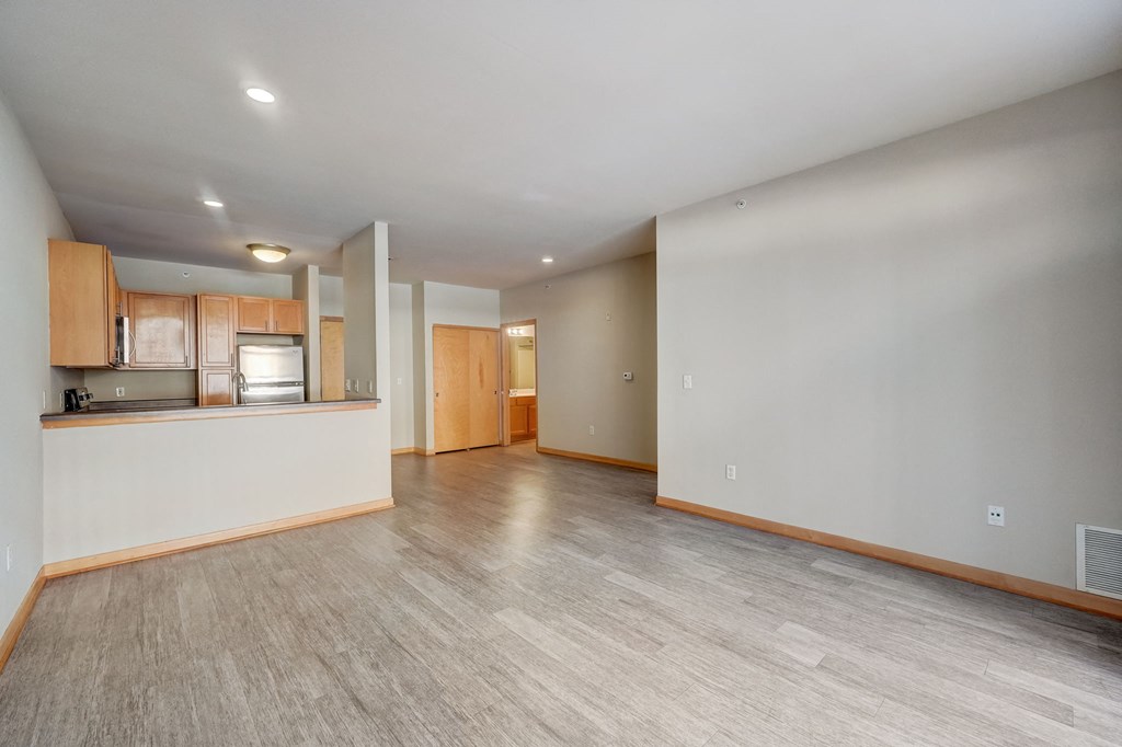 the living room and kitchen of an empty house with wood flooring