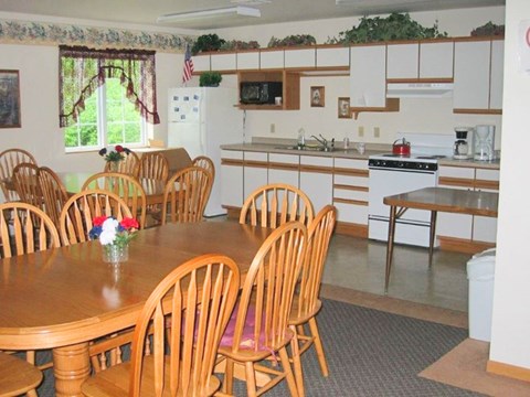 A kitchen with a table and chairs in front of it.