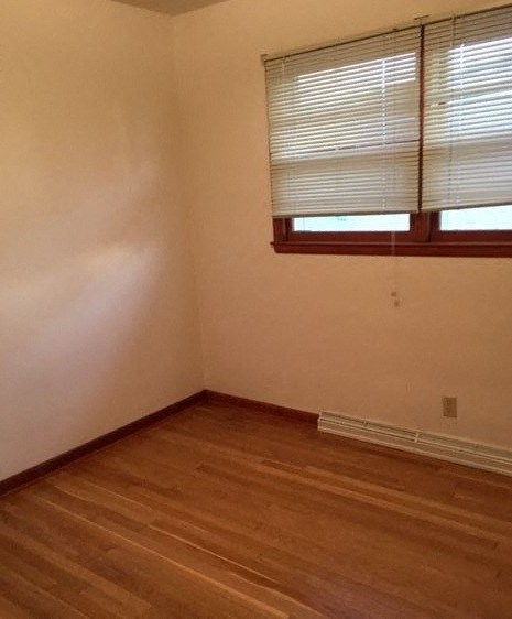 an empty room with a window and wooden floors