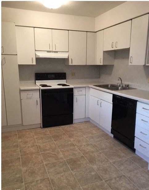 an empty kitchen with white cabinets and black appliances