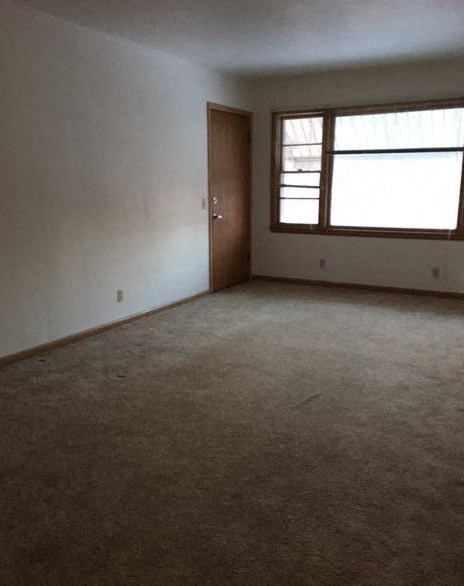 an empty living room with a door and a window