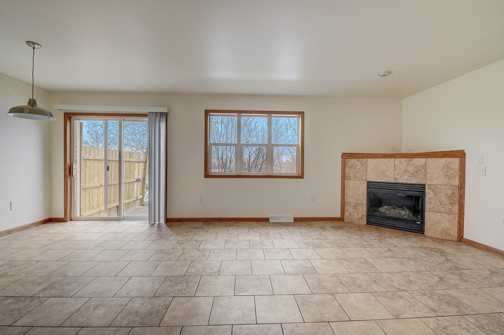 an empty living room with a fireplace and a sliding glass door