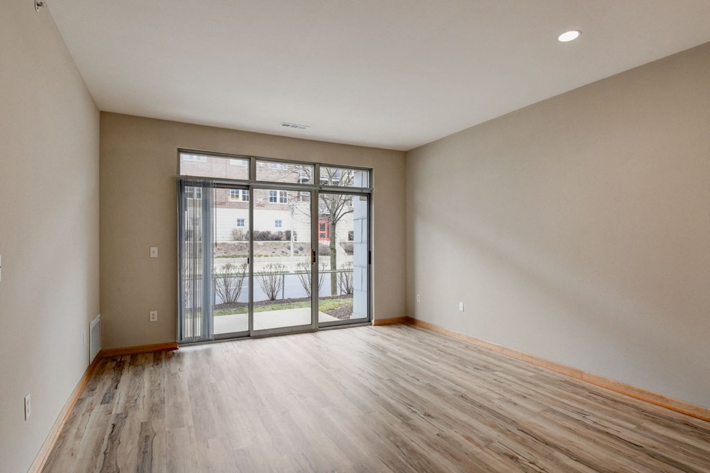 an empty living room with a sliding glass door to a balcony
