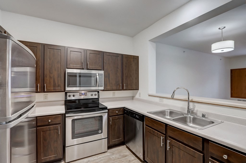 an empty kitchen with wooden cabinets and stainless steel appliances