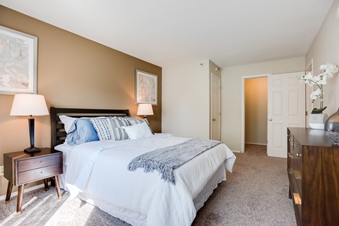 A bedroom with a large bed and a nightstand with a lamp.