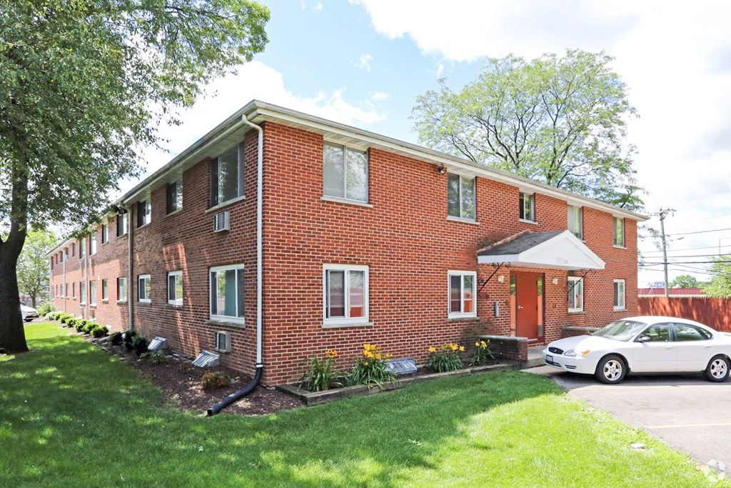 a red brick apartment building with a white car parked in front