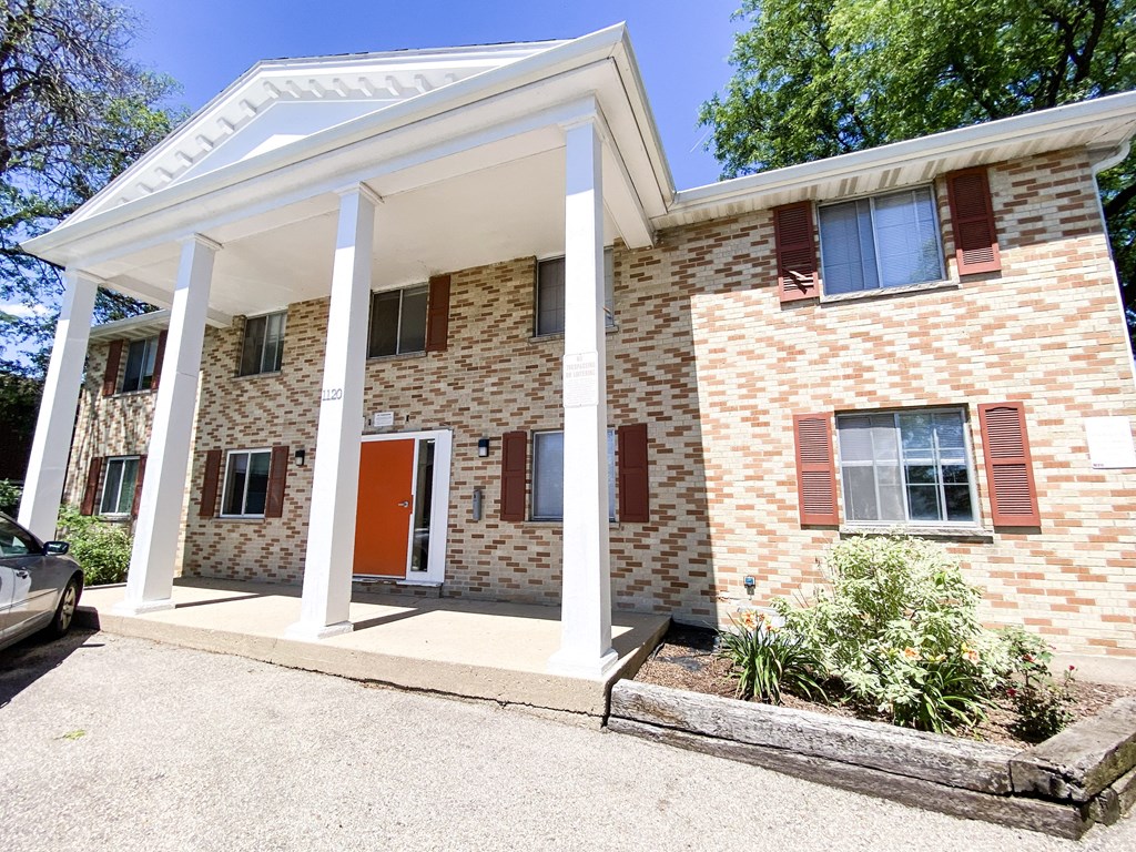 the front of a brick building with columns and a porch