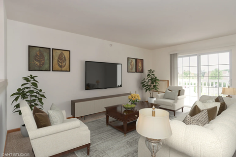 A living room with a white couch, a brown armchair, a wooden coffee table, and a flat-screen TV mounted on the wall.