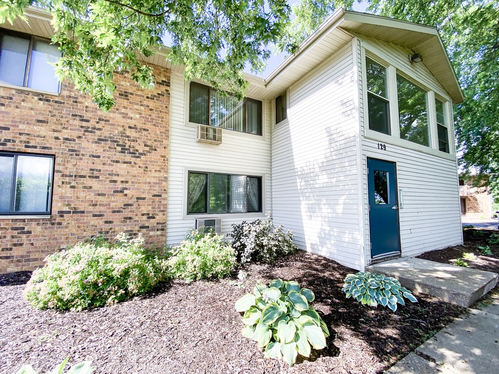 the front of a white house with a blue door